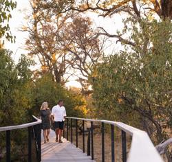 Couple holding hands walking along raised walkway 