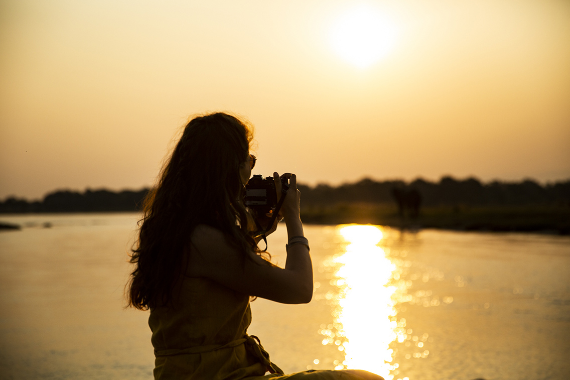 Guest with a camera overlooking the river at sunset in Mana Pools National Park, Zimbabwe