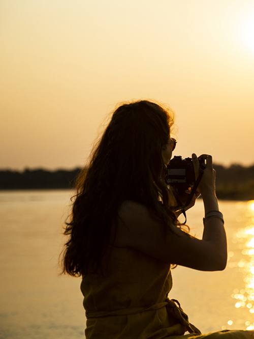 Guest with a camera overlooking the river at sunset in Mana Pools National Park, Zimbabwe