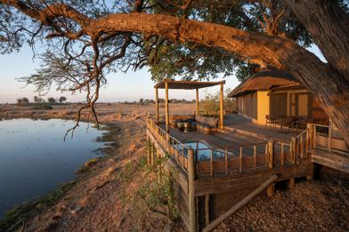A deck with a swimming pool overlooking a channel of water