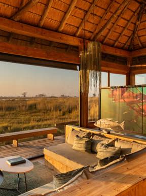 A lavish, airy tented suite at Vumbura Plains, built on a raised wooden deck with a high, sloping canvas roof. The room is decorated in soft, natural colors, emphasizing the contemporary African luxury of the Okavango Delta camp.