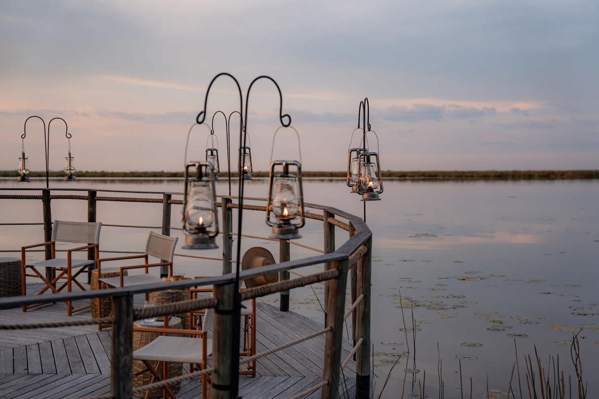 A five-star safari room where the interior seamlessly blends into the Okavango Delta landscape. The design utilizes wood and canvas, creating an eco-friendly, minimalist luxury look with large glass panels to maximize nature views.