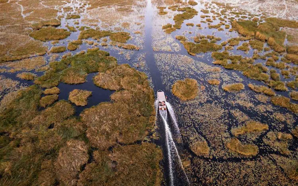 A speed boat cruising along the channels of the Okavango Delat at Wilderness Vumbura
