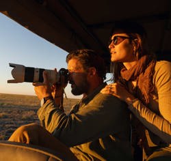 Guests on a game drive vehicle taking photos of sightings at Mokete