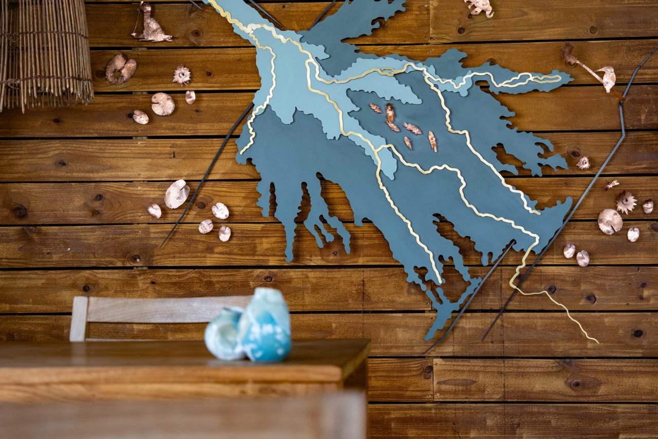 Lodge decor with a wooden wall featuring a stylized, laser-cut art piece mapping the Okavango Delta's formation, complete with small bronze animal figures.
