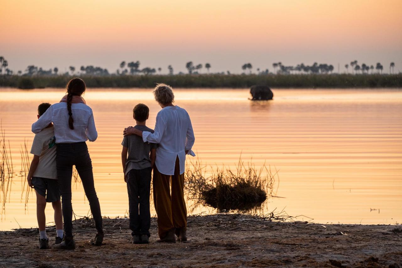 Family on safari at sunset with an elephant in the river