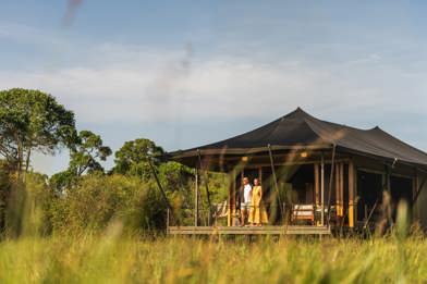 Guests standing on the private tent deck at Wilderness Mara Kenya