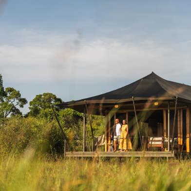 Guests standing on the private tent deck at Wilderness Mara Kenya