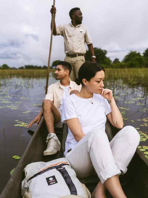 A couple floating along the Okavango Delta in a mokoro at Vumbura