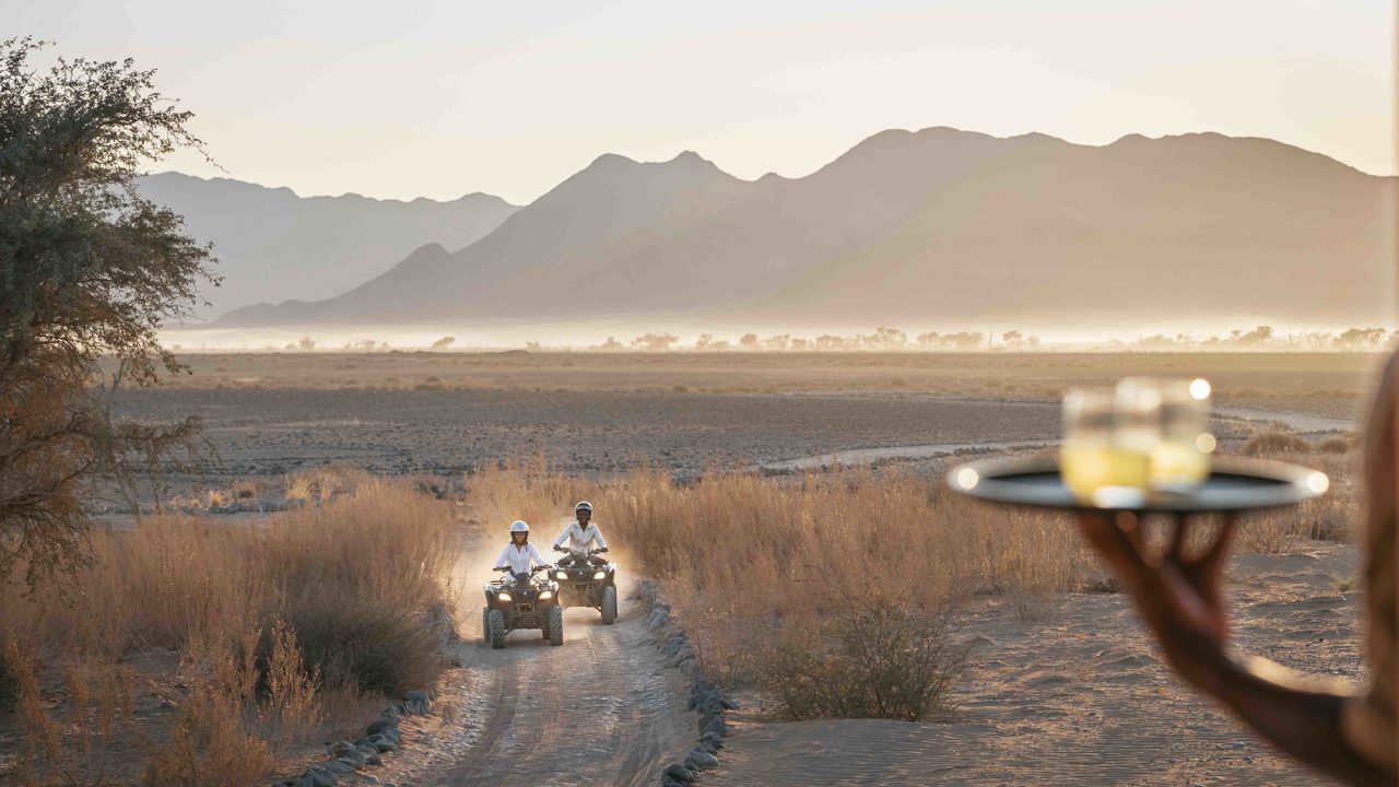 A couple exploring the Namib desert on quad bikes on their way to a sundowner