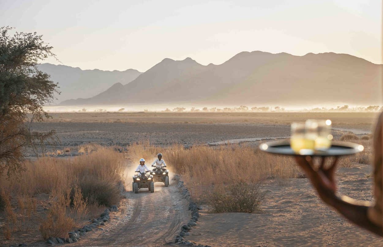 A couple exploring the Namib desert on quad bikes on their way to a sundowner