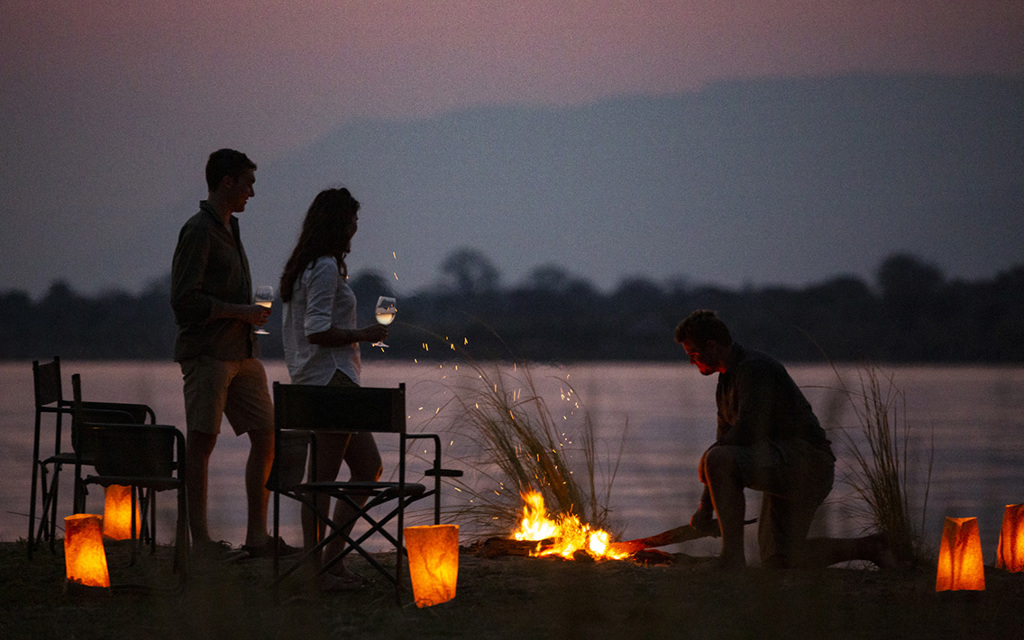 Guests enjoying sundowners around a campfire in Mana Pools National Park, Zimbabwe