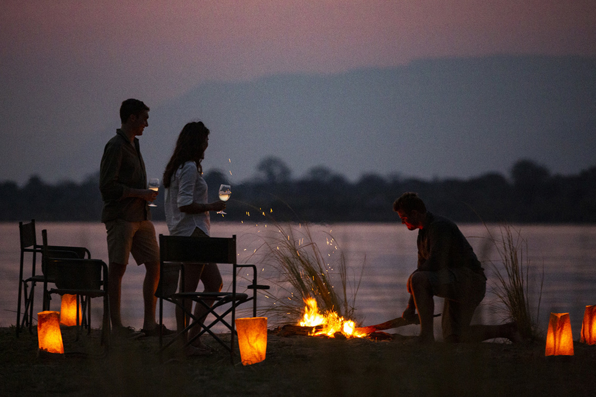 Guests enjoying sundowners around a campfire in Mana Pools National Park, Zimbabwe